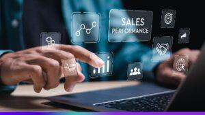 Pessoa interagindo com um laptop, tocando em ícones digitais flutuantes relacionados a vendas, como gráfico de desempenho, carrinho de compras, aperto de mãos e "Sales Performance" em destaque. Representa o conceito de automação e análise de performance em vendas.