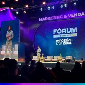 Palestrante em palco no Fórum E-commerce 360, com projeção “Marketing & Vendas” e slogan “Impossível Sair Igual”.