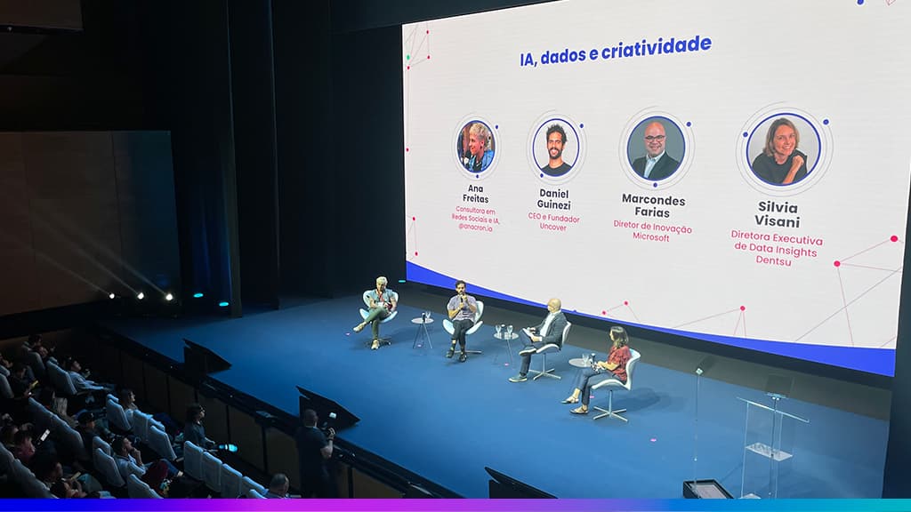 Painel do Adtech & Branding 2025 com quatro palestrantes no palco e telão exibindo o tema “IA, dados e criatividade” junto aos nomes e cargos dos participantes.