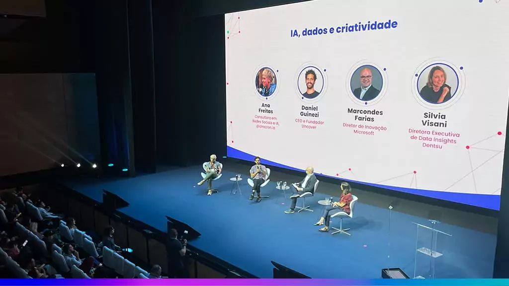 Painel do Adtech & Branding 2025 com quatro palestrantes no palco e tel&atilde;o exibindo o tema &ldquo;IA, dados e criatividade&rdquo; junto aos nomes e cargos dos participantes.