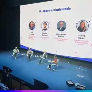 Painel do Adtech & Branding 2025 com quatro palestrantes no palco e telão exibindo o tema “IA, dados e criatividade” junto aos nomes e cargos dos participantes.
