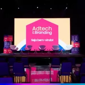 Palco do Adtech & Branding 2025 com telão “Seja bem-vindo!” e cadeiras alinhadas para o painel.