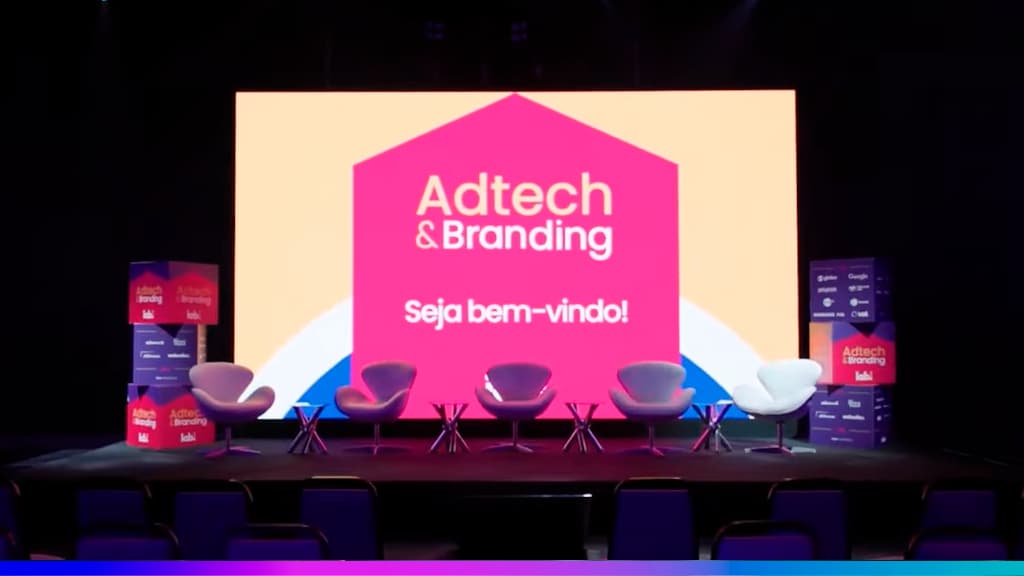 Palco do Adtech & Branding 2025 com telão “Seja bem-vindo!” e cadeiras alinhadas para o painel.