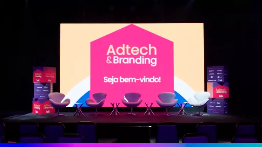 Palco do Adtech & Branding 2025 com telão “Seja bem-vindo!” e cadeiras alinhadas para o painel.