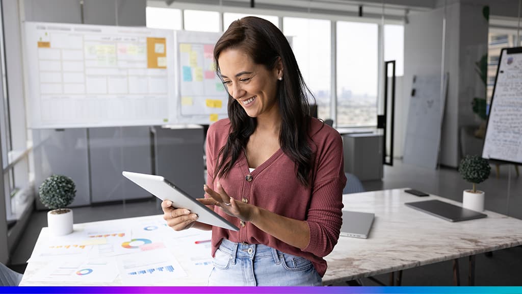 Business Intelligence na prática: analista com tablet em escritório, ao lado de relatórios e dashboards.