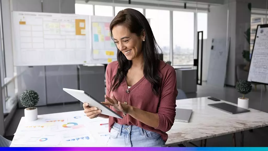 Business Intelligence na prática: analista com tablet em escritório, ao lado de relatórios e dashboards.