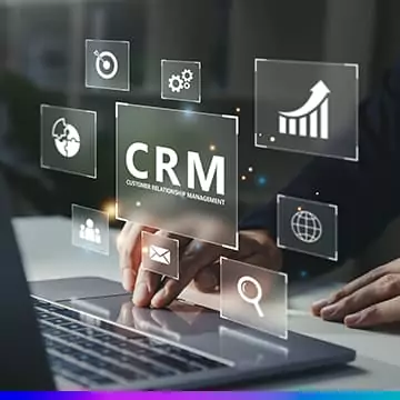 Pessoa usando notebook com ícones digitais flutuantes representando ferramentas de CRM, como gráficos, e-mail e pesquisa.