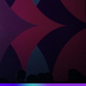 Imagem abstrata com formas geométricas em tons de rosa, roxo e azul escuro ao fundo, com silhuetas de pessoas na parte inferior, representando a atmosfera de um evento.
